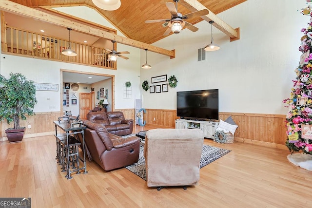 living room with a wainscoted wall, wood finished floors, visible vents, and wooden walls