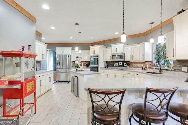 kitchen featuring beverage cooler, appliances with stainless steel finishes, tasteful backsplash, and a sink