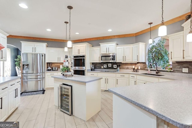 kitchen featuring wine cooler, appliances with stainless steel finishes, a sink, light countertops, and backsplash