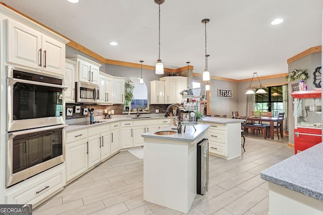 kitchen with a center island with sink, decorative backsplash, appliances with stainless steel finishes, light countertops, and a sink