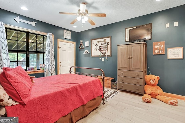 bedroom with a ceiling fan, baseboards, light wood-style floors, and a textured ceiling