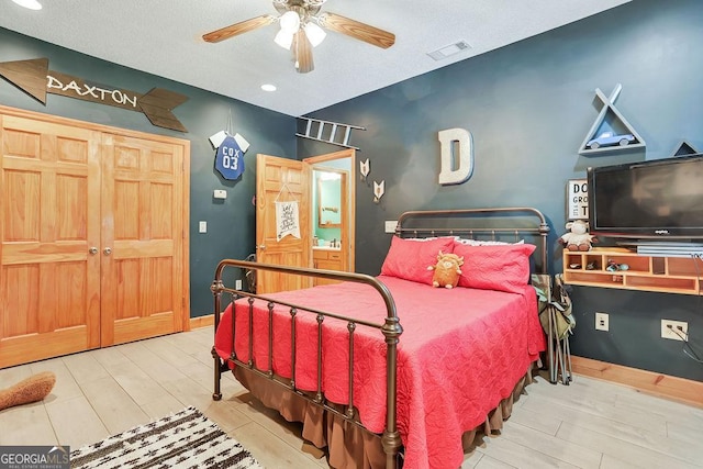 bedroom with a ceiling fan, wood finished floors, visible vents, and baseboards