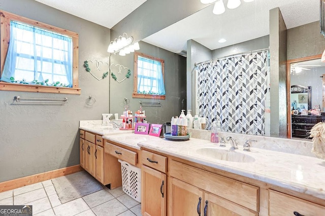 bathroom featuring a textured ceiling, double vanity, a sink, and tile patterned floors