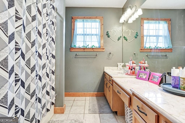 full bath featuring plenty of natural light, tile patterned flooring, vanity, and baseboards