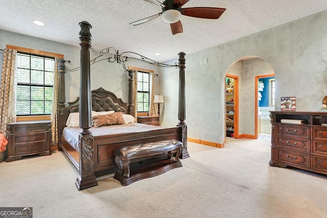 carpeted bedroom with baseboards, arched walkways, ceiling fan, a textured ceiling, and recessed lighting