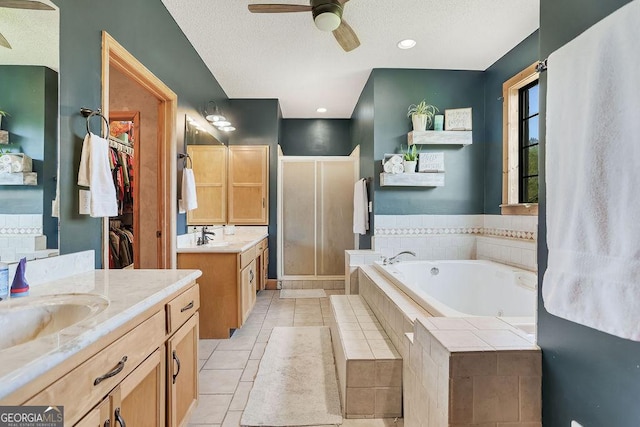 full bath featuring two vanities, a jetted tub, a textured ceiling, a shower stall, and a sink