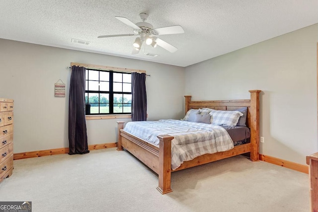 bedroom with light colored carpet, visible vents, and a textured ceiling