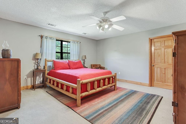 bedroom featuring a textured ceiling, a ceiling fan, visible vents, and light colored carpet