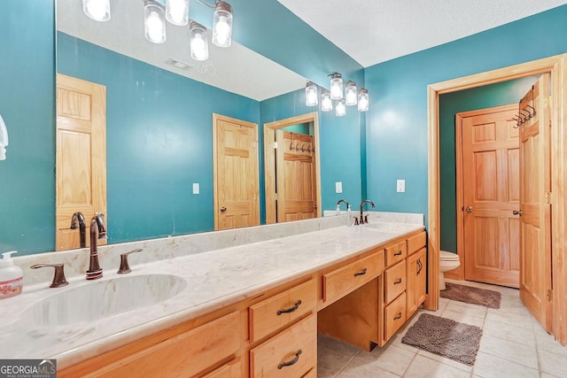 full bathroom with double vanity, toilet, a sink, and tile patterned floors