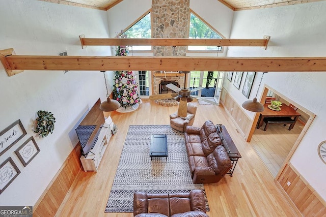 living area with a fireplace, wood finished floors, a towering ceiling, and a healthy amount of sunlight