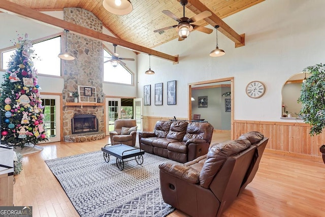 living area with wooden ceiling, a wainscoted wall, a stone fireplace, and hardwood / wood-style flooring