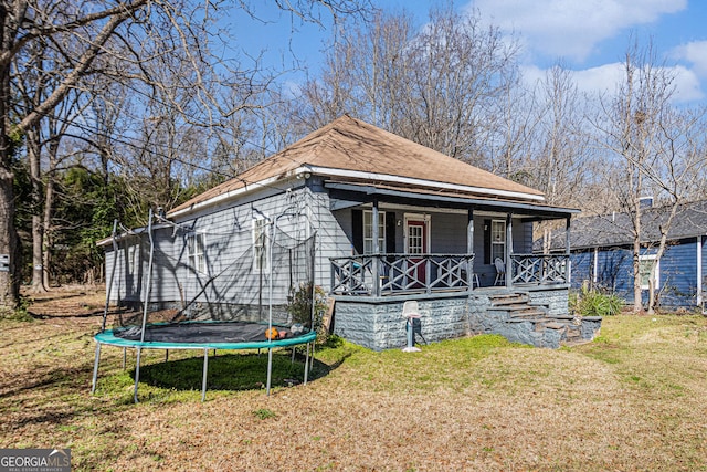 view of front facade with covered porch, a trampoline, and a front yard