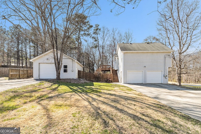 view of property exterior featuring a garage, an outbuilding, a lawn, and fence