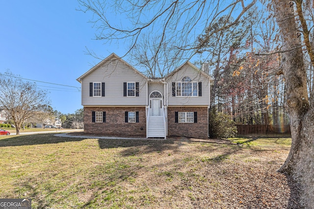 bi-level home featuring a front yard, fence, and brick siding