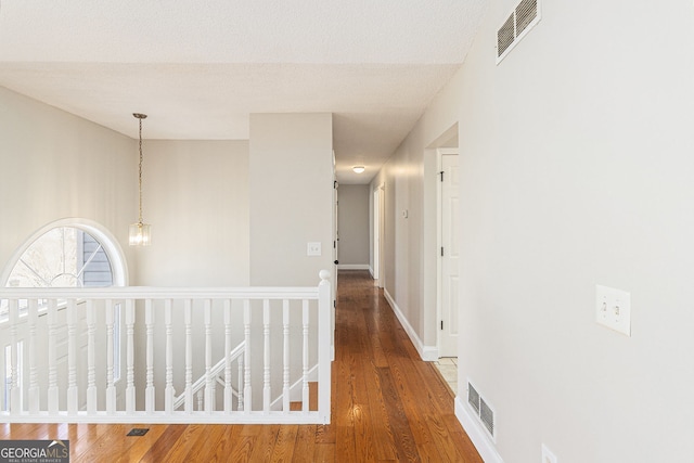 hallway featuring wood finished floors, visible vents, and baseboards