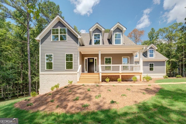 view of front of property featuring a porch, brick siding, a front yard, and a shingled roof