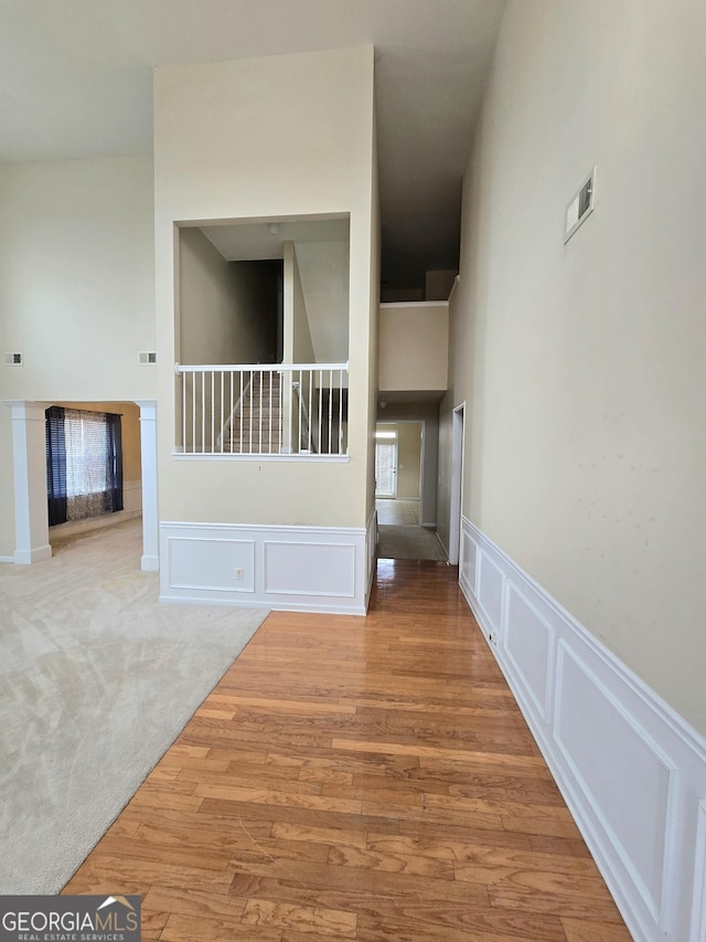 interior space with a decorative wall, light carpet, a towering ceiling, light wood-style floors, and stairs