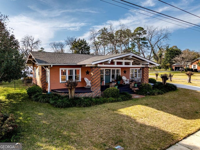 view of front facade with a shingled roof, covered porch, brick siding, and a front lawn