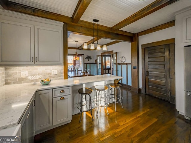 kitchen featuring beam ceiling, dark wood finished floors, tasteful backsplash, light stone countertops, and a peninsula