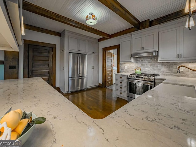 kitchen with appliances with stainless steel finishes, gray cabinets, decorative backsplash, and light stone countertops