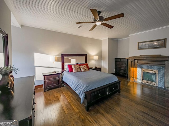 bedroom featuring ornamental molding, a fireplace, ceiling fan, and hardwood / wood-style flooring