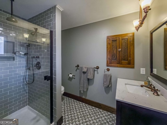 bathroom with toilet, a stall shower, baseboards, and vanity