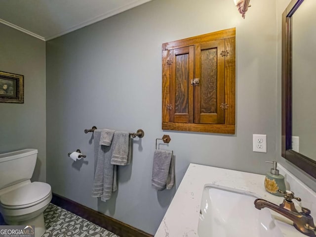 bathroom with toilet, baseboards, a sink, and ornamental molding