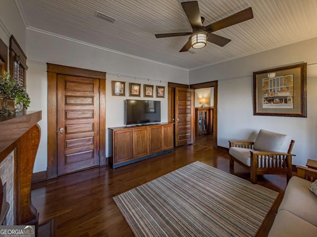 living area with ornamental molding, dark wood-style flooring, visible vents, and a ceiling fan