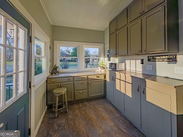 kitchen featuring ornamental molding, stainless steel microwave, and plenty of natural light