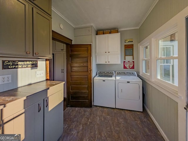 clothes washing area with cabinet space, baseboards, dark wood finished floors, crown molding, and washing machine and dryer