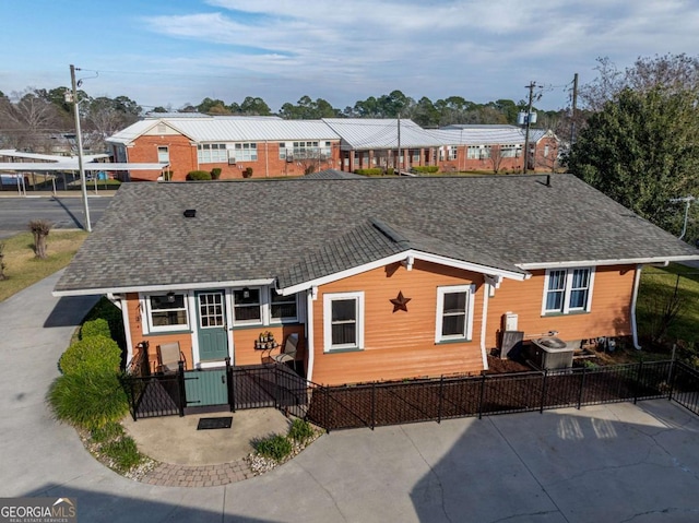 rear view of property featuring a fenced front yard and roof with shingles