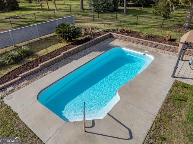 view of swimming pool with fence and a lawn