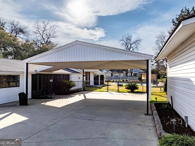 view of patio featuring a detached carport, concrete driveway, and fence