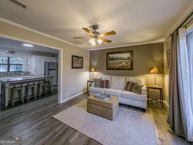 living area with visible vents, baseboards, ceiling fan, wood finished floors, and crown molding