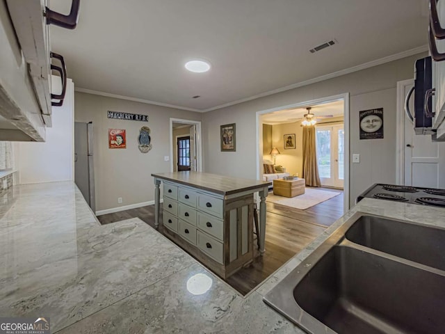 kitchen with a sink, visible vents, french doors, dark wood finished floors, and crown molding