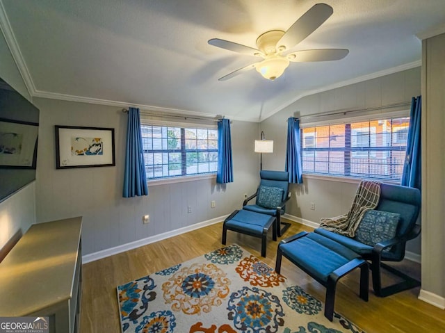 living area featuring lofted ceiling, ceiling fan, wood finished floors, baseboards, and ornamental molding