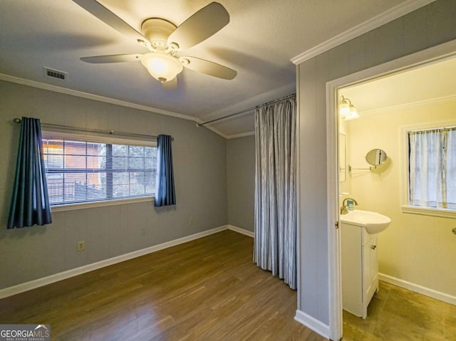 unfurnished bedroom featuring a sink, wood finished floors, visible vents, a ceiling fan, and ornamental molding