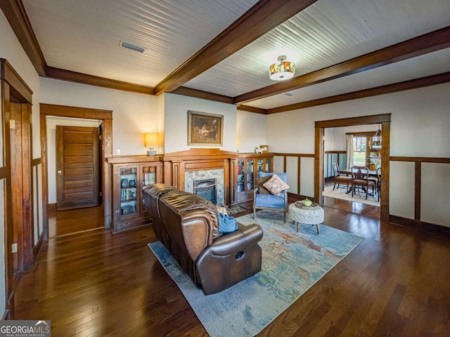 living area with a fireplace, beamed ceiling, visible vents, and wood finished floors