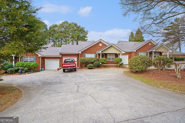 ranch-style home featuring a garage, metal roof, brick siding, and driveway