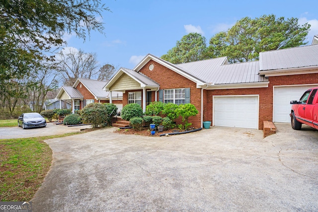 ranch-style house with metal roof, concrete driveway, brick siding, and an attached garage