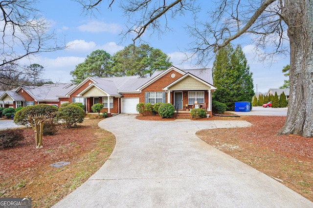 single story home with covered porch, driveway, brick siding, and a garage