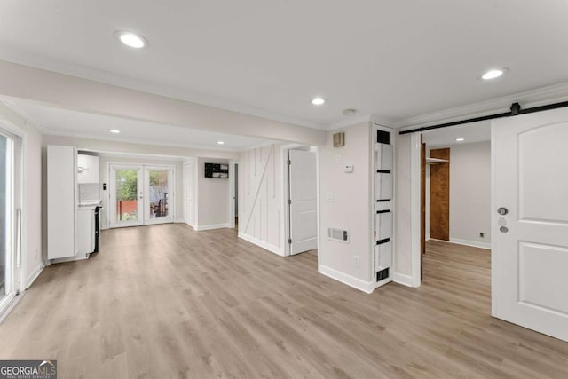 interior space with crown molding, light wood finished floors, recessed lighting, visible vents, and a barn door