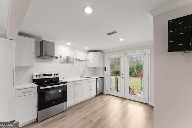 kitchen with stainless steel appliances, visible vents, white cabinetry, french doors, and wall chimney range hood