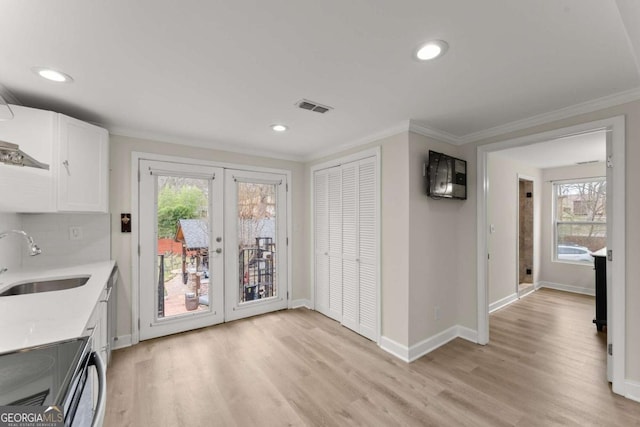 kitchen featuring electric stove, visible vents, a sink, and ornamental molding