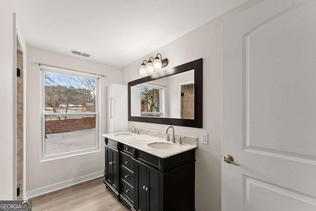 full bathroom with double vanity, visible vents, a sink, and wood finished floors