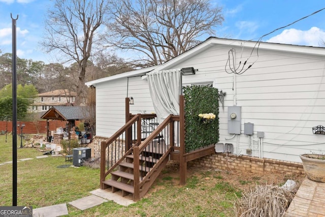 rear view of house featuring cooling unit and a yard