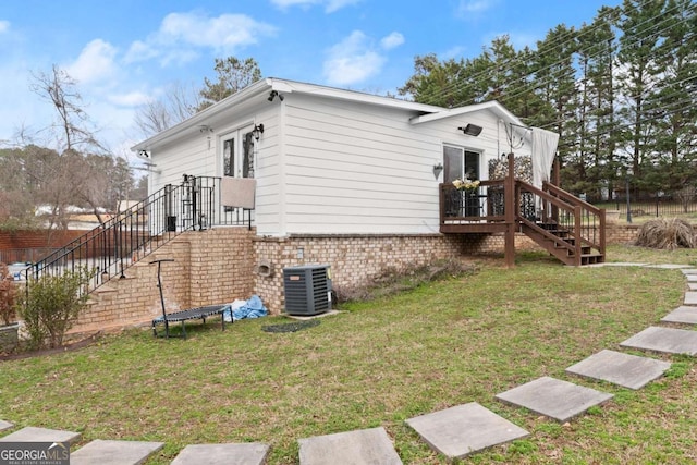 view of side of home with french doors, central AC unit, a lawn, and brick siding