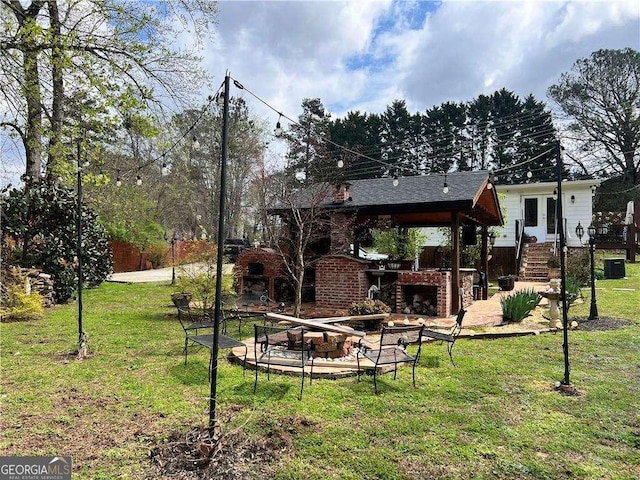 view of yard with central air condition unit, a patio area, and an outdoor brick fireplace