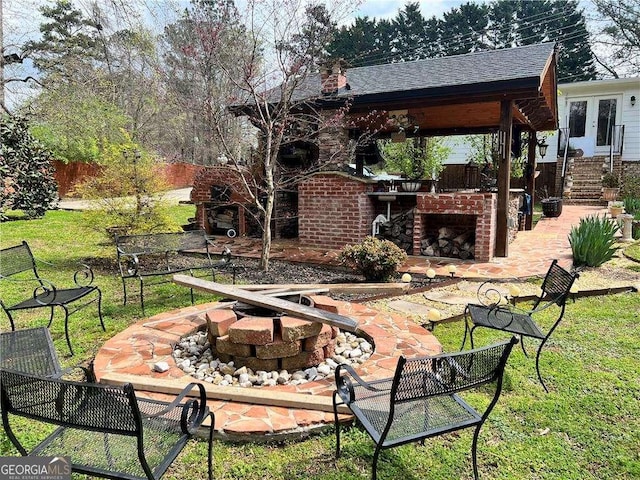 view of patio / terrace with an outdoor brick fireplace, fence, and french doors