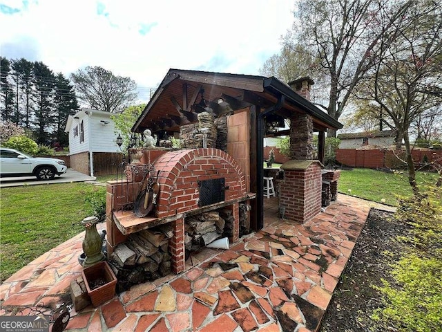 view of patio featuring an outdoor brick fireplace and fence